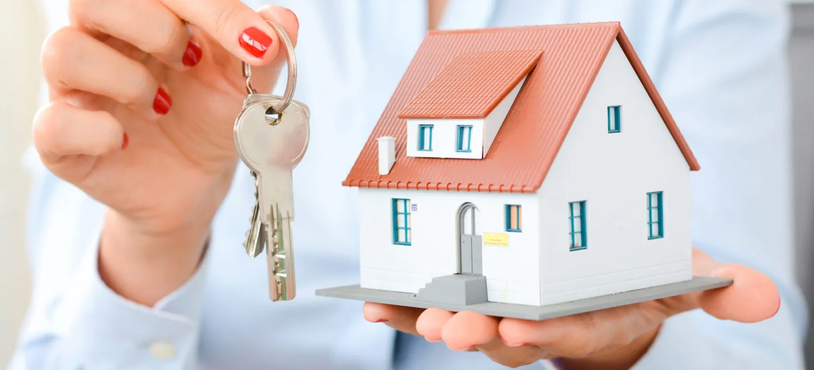 uying a house concept with woman hands holding a model house and house keys